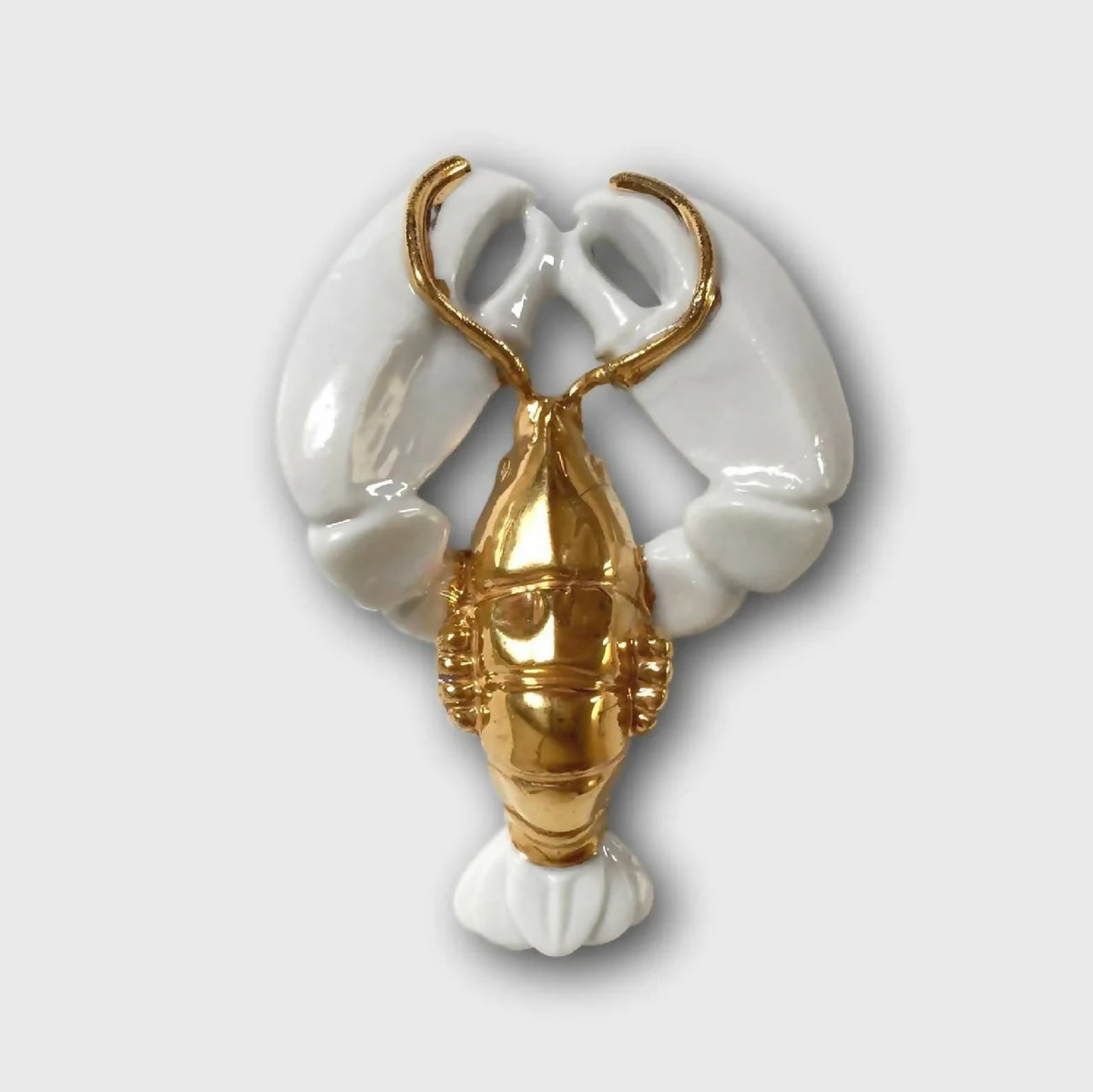 Porte-couvert homard blanc et doré, forme de pinces et queue décoratives.