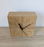 Horloge de bureau carrée en chêne clair, vue en angle, aiguilles noires et repères colorés.
