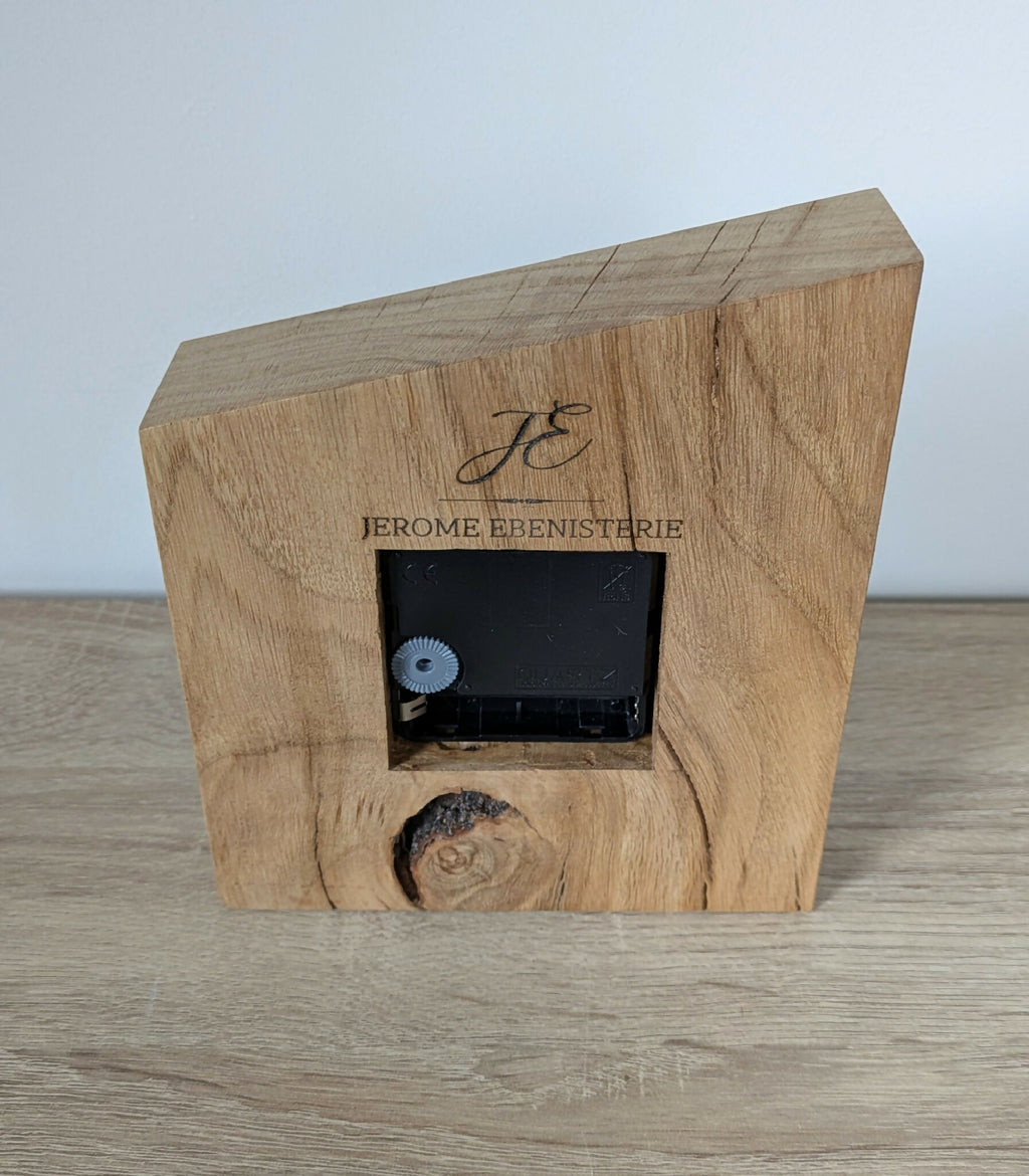 Horloge de bureau en bois clair avec mécanisme noir encastré et logo gravé.