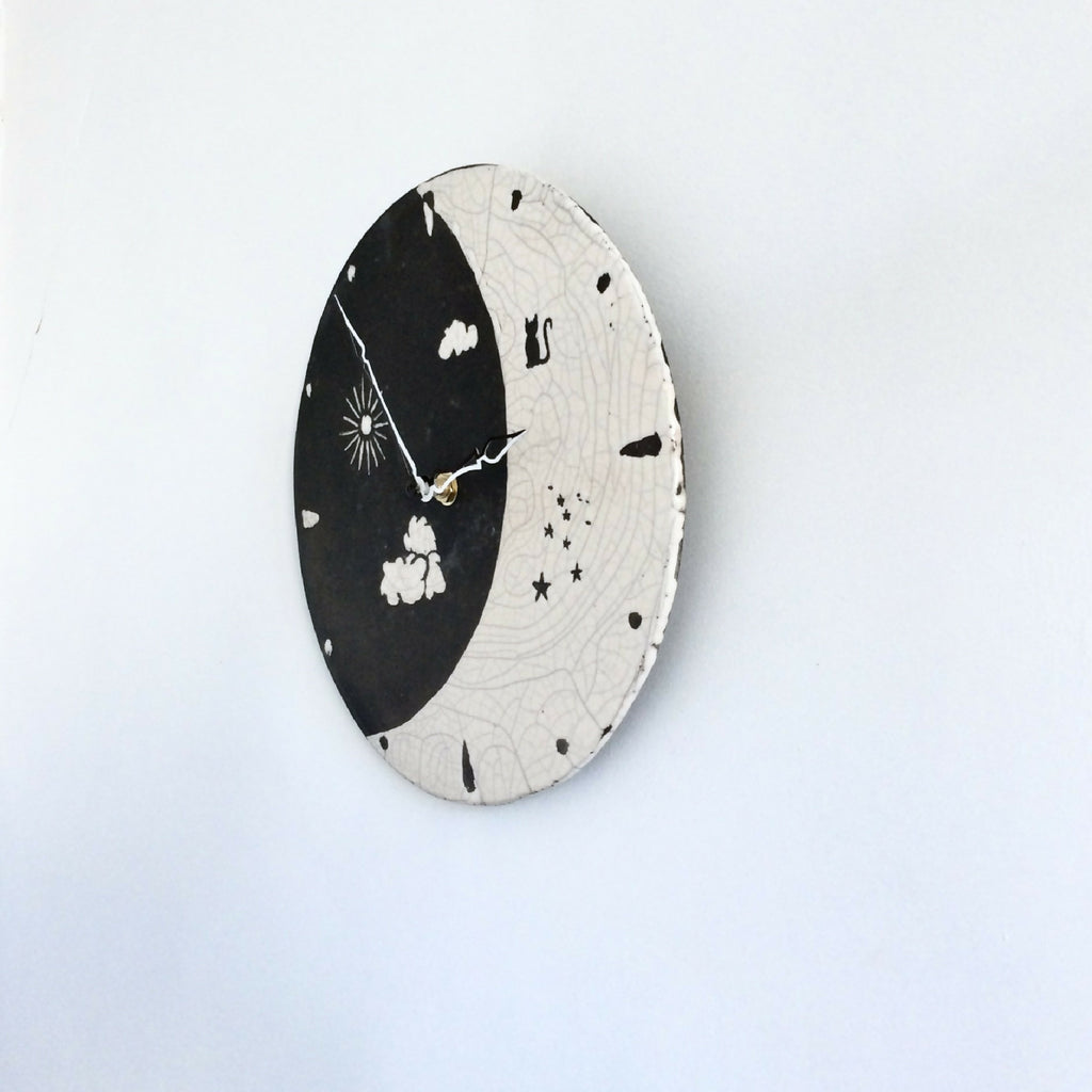 Horloge murale ronde noir et ivoire, cadran Jour et Nuit en vue inclinée, aiguilles et motifs