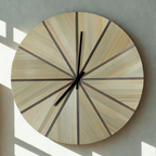 Horloge murale ronde en paille beige et marqueterie marron, cadran à rayons et aiguilles noires.