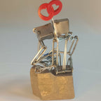 Sculpture en fils d’acier sur socle doré, couple et cœur rouge, angle rapproché