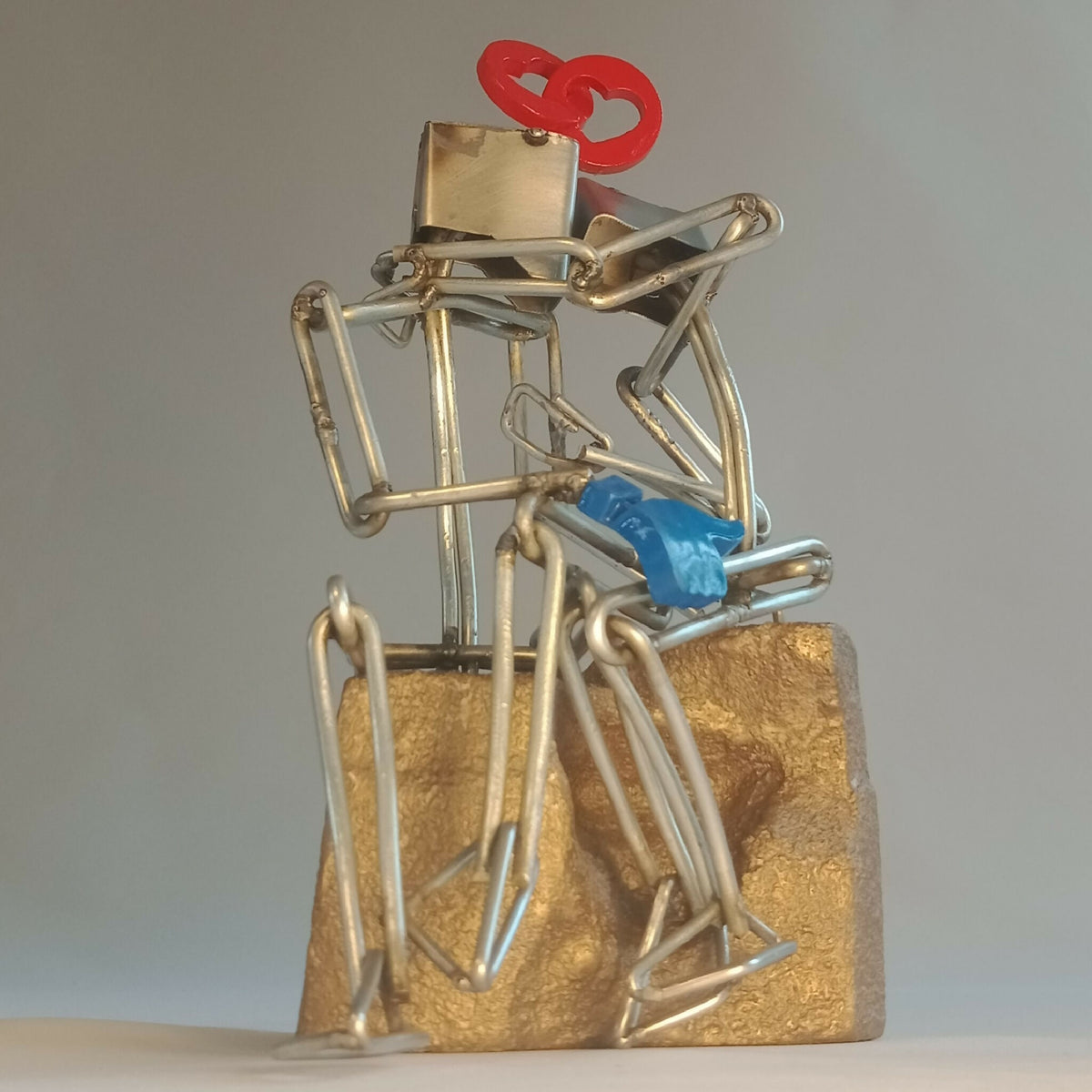 Sculpture en fils d’acier sur socle doré, couple en structure métallique, cœur rouge