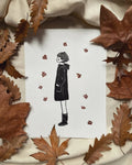 Impression sur papier blanc : silhouette féminine noire avec étoiles rouges, décor automnal.
