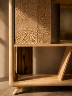 Bibliothèque en bois : panneau texturé et compartiment inférieur visible, pieds inclinés.