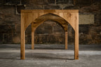 Table en bois avec piètement ajouré en arc, vue de face.