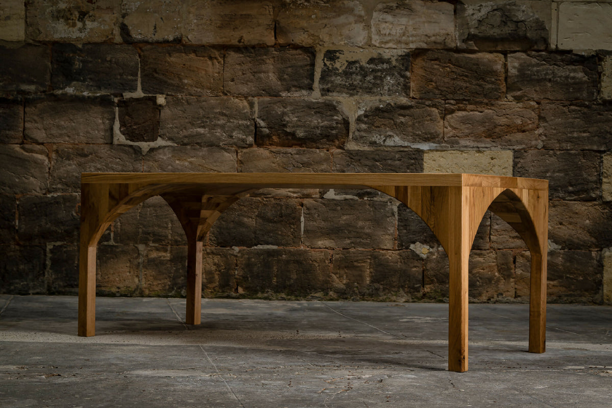 Table en bois avec piètement en arc et plateau rectangulaire.
