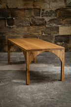 Table en bois avec piètement en arc et plateau rectangulaire, vue de trois-quarts.