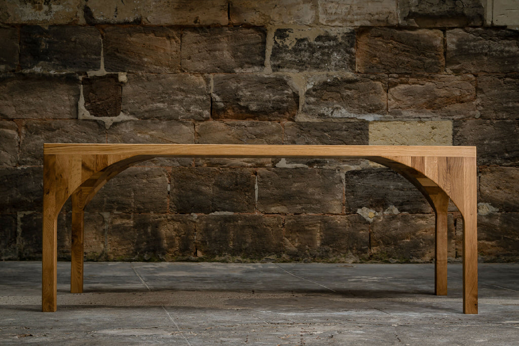 Table rectangulaire en bois clair, pieds arqués et traverse centrale