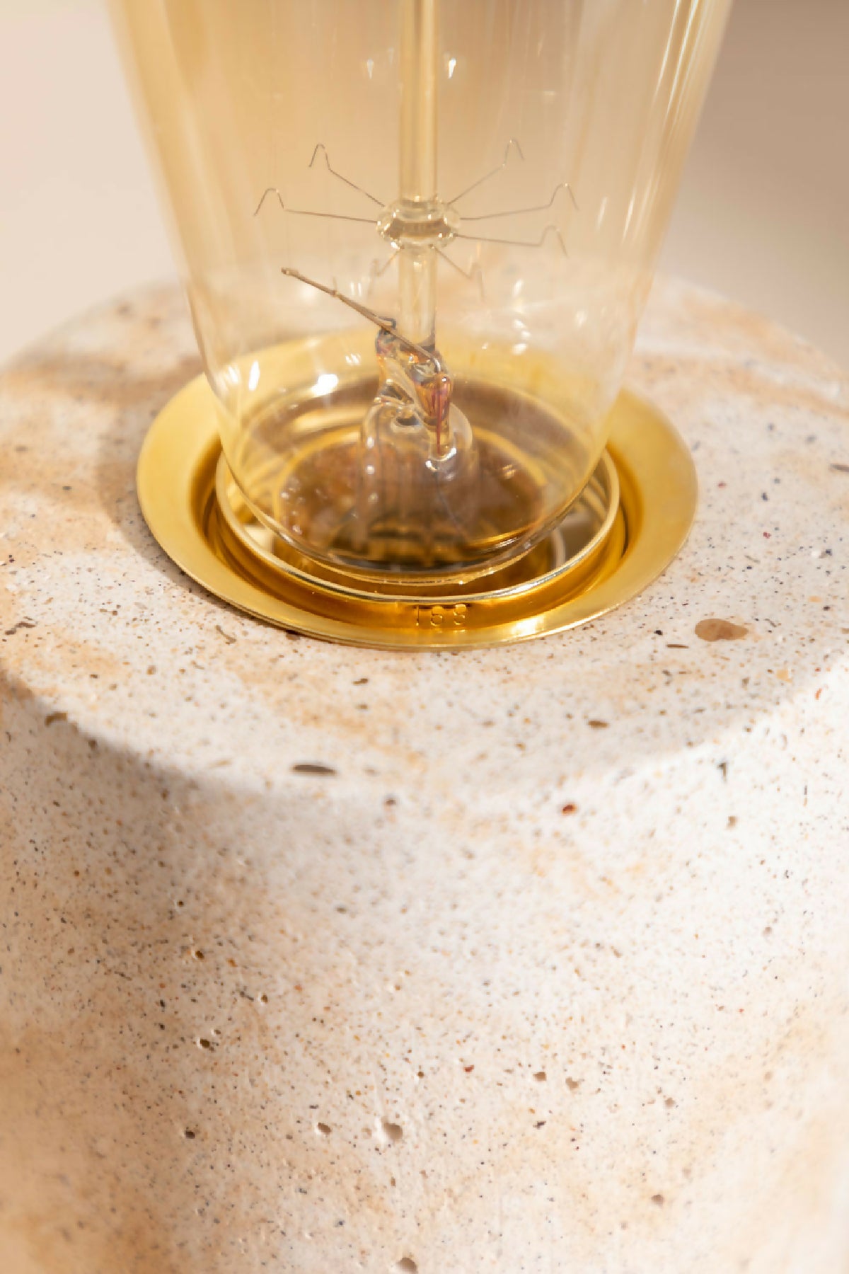 Lampe à poser : base dorée circulaire et ampoule en verre sur socle beige texturé