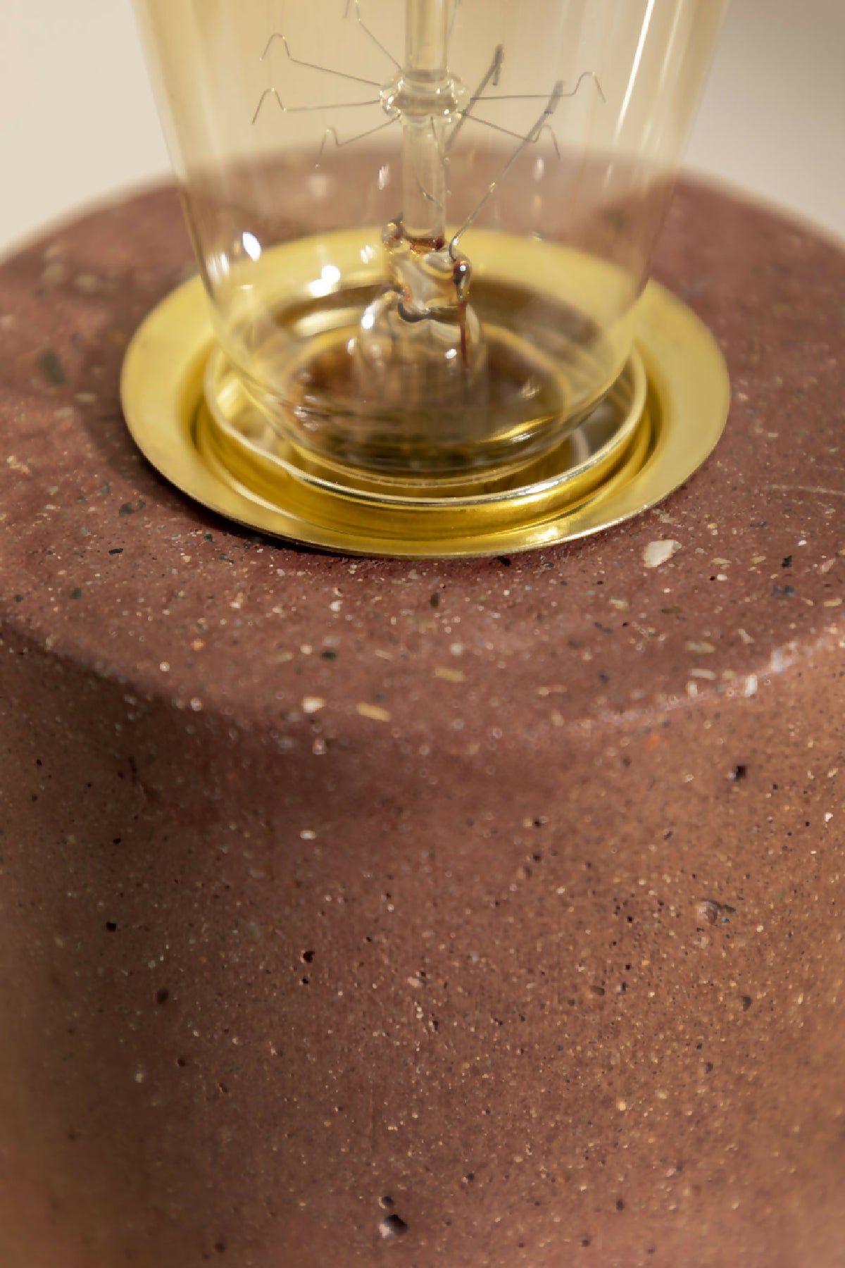 Socle rond brun texturé avec base dorée de lampe à poser et ampoule en verre