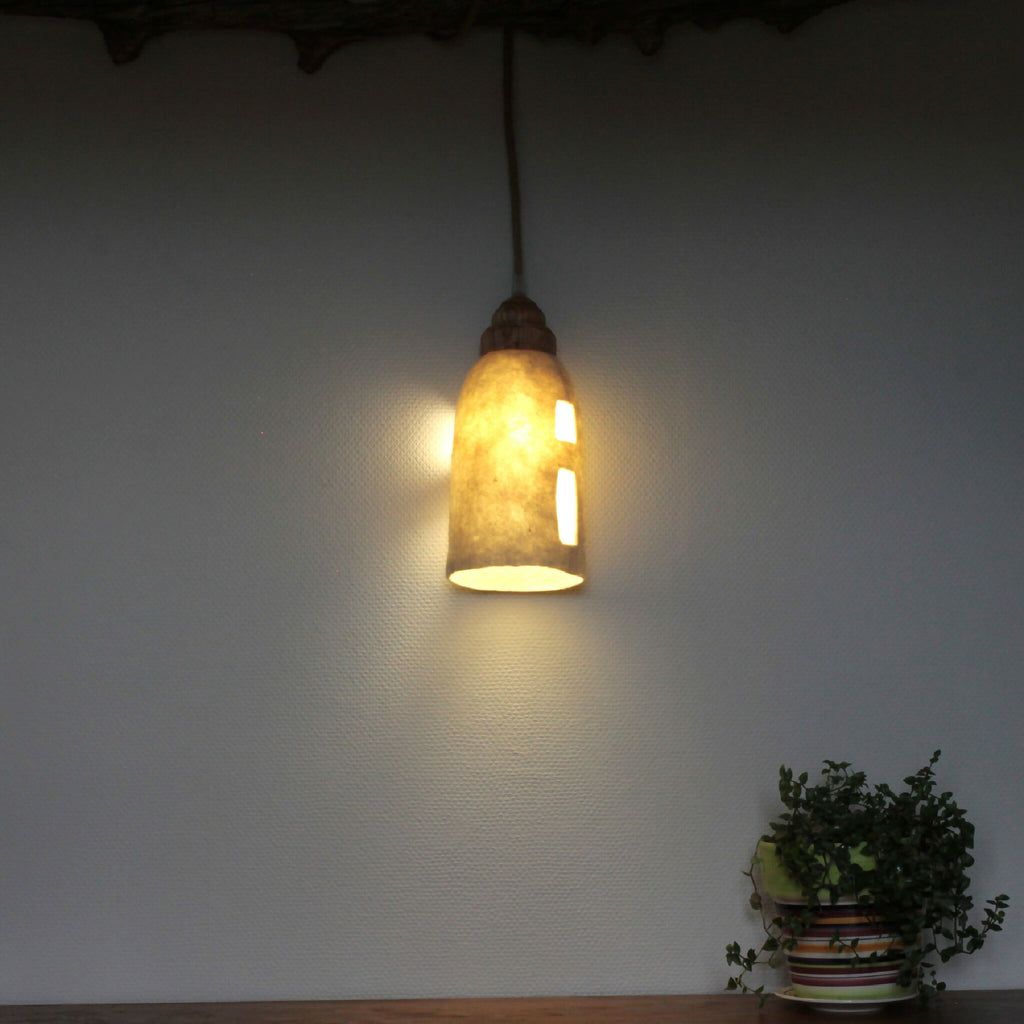 Lampe baladeuse allumée, abat-jour en feutre clair avec ouvertures découpées, lumière chaude