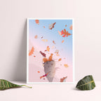 Affiche encadrée d’un chat gris sautant parmi des feuilles aux tons orange et bleu.