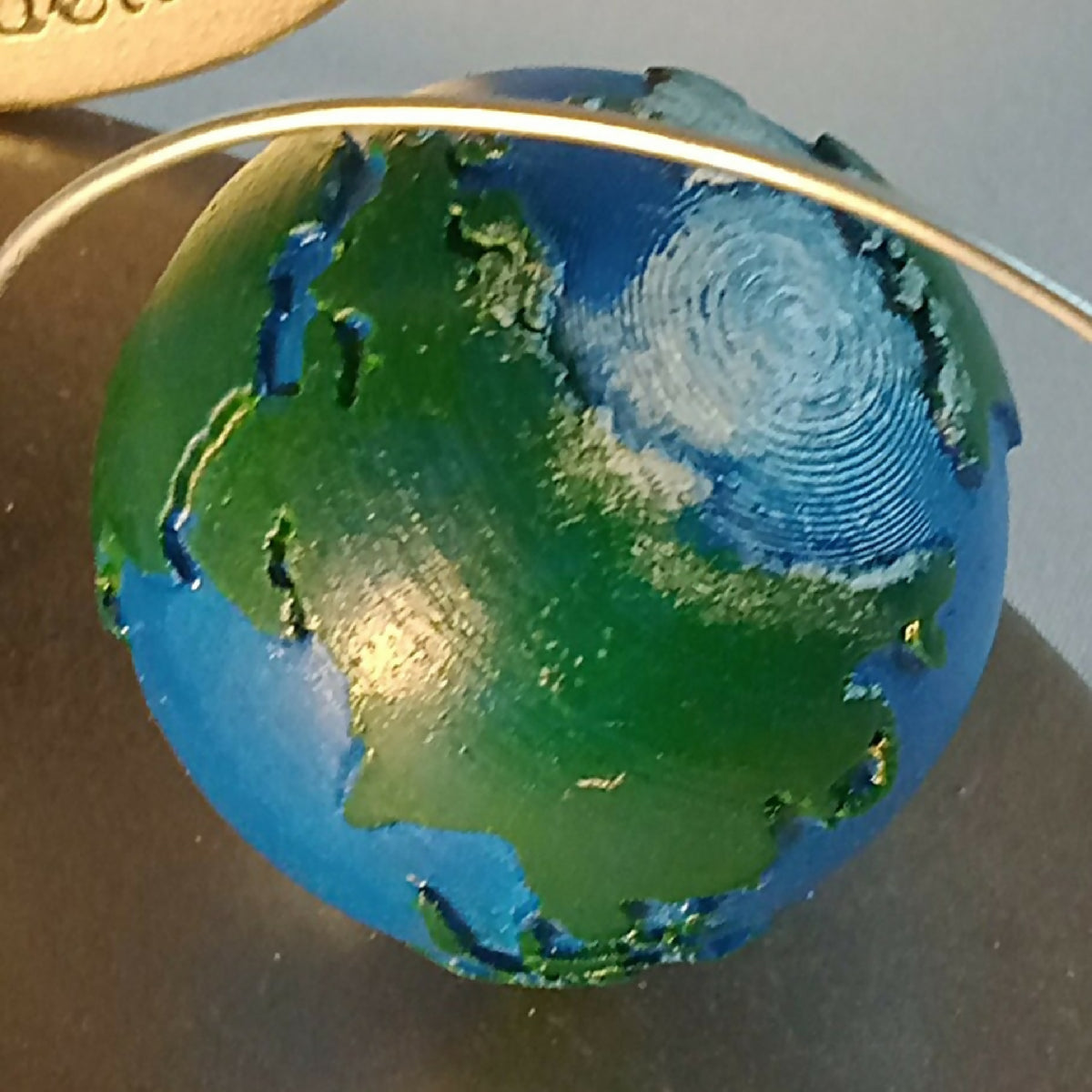 Globe décoratif bleu-vert avec contour argenté et tige métallique
