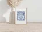 Tirage A4 encadré, motif abstrait bleu texturé, posé près d’un vase beige.