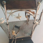 Intérieur de manège décoratif : figurines, arche métallique et surface tissée grise.