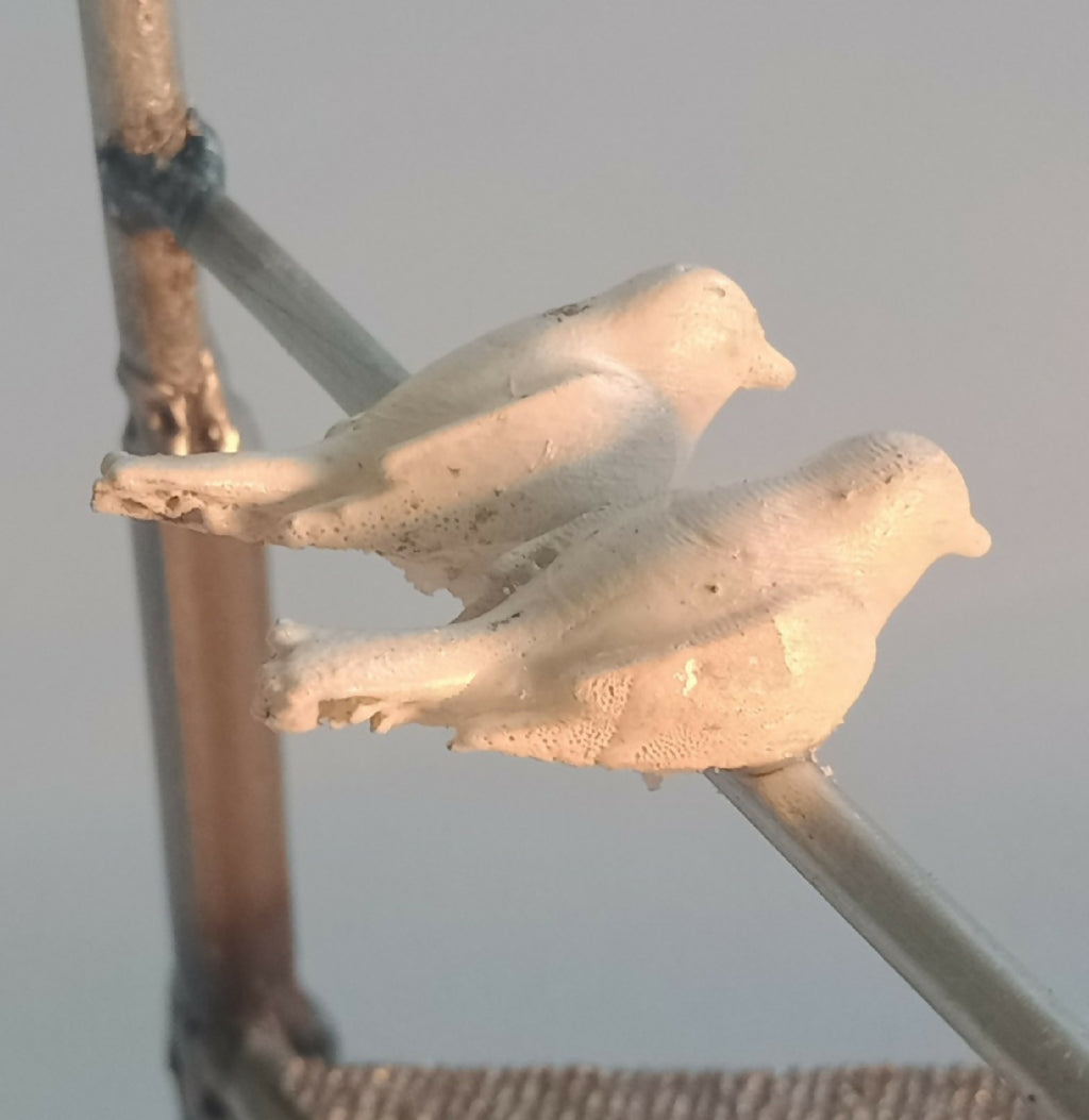 Deux oiseaux en métal blanc posés sur une barre du manège décoratif.