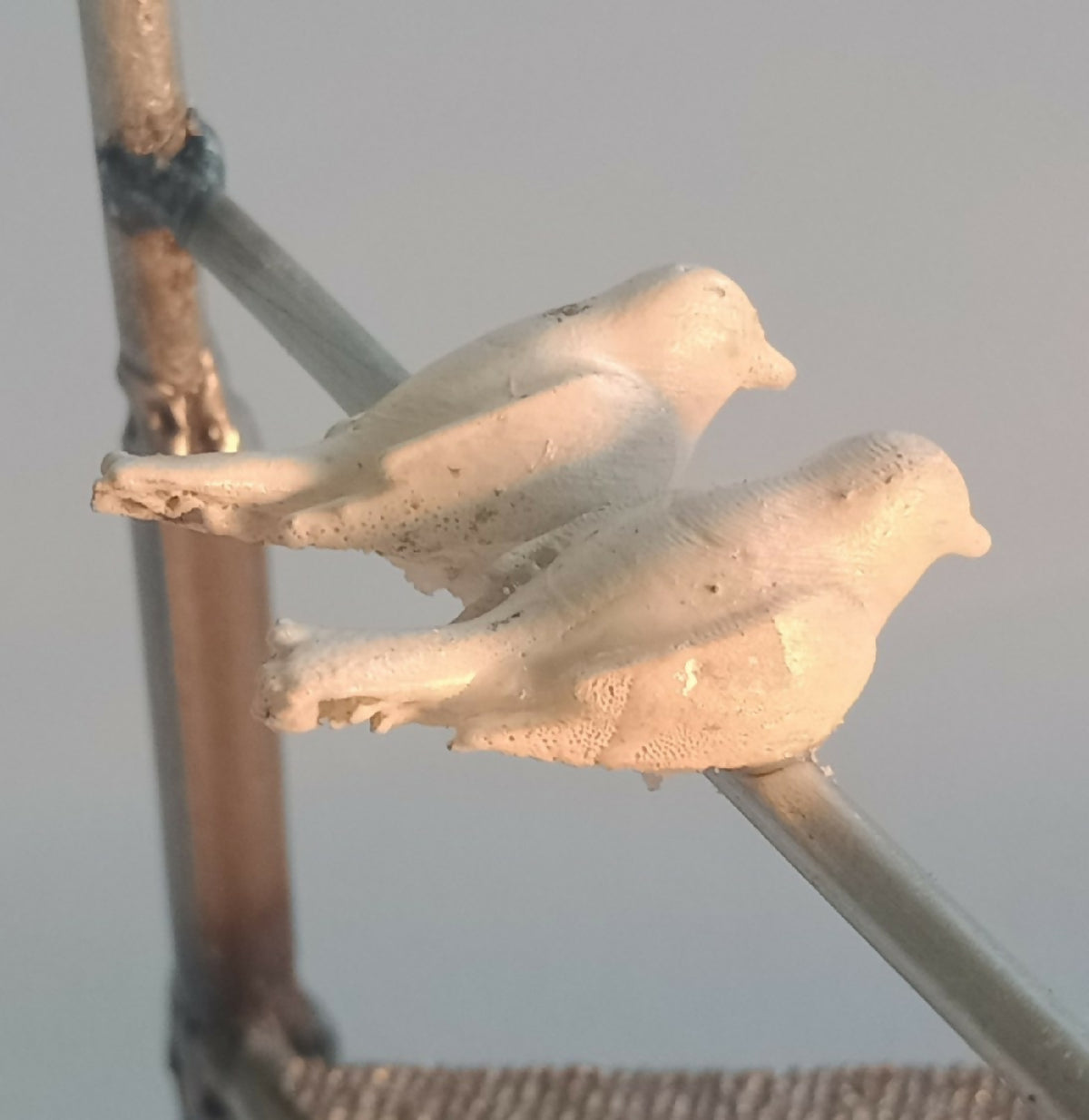 Deux oiseaux en métal blanc posés sur une barre du manège décoratif.