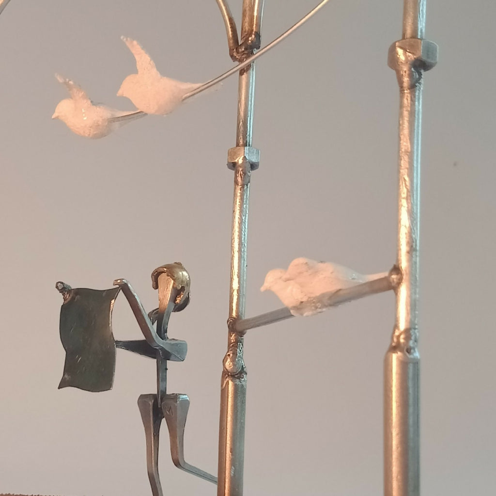 Figurine en robe noire tenant une canne, sur manège décoratif, avec oiseau en blanc.