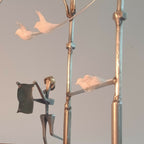 Figurine en robe noire tenant une canne, sur manège décoratif, avec oiseau en blanc.