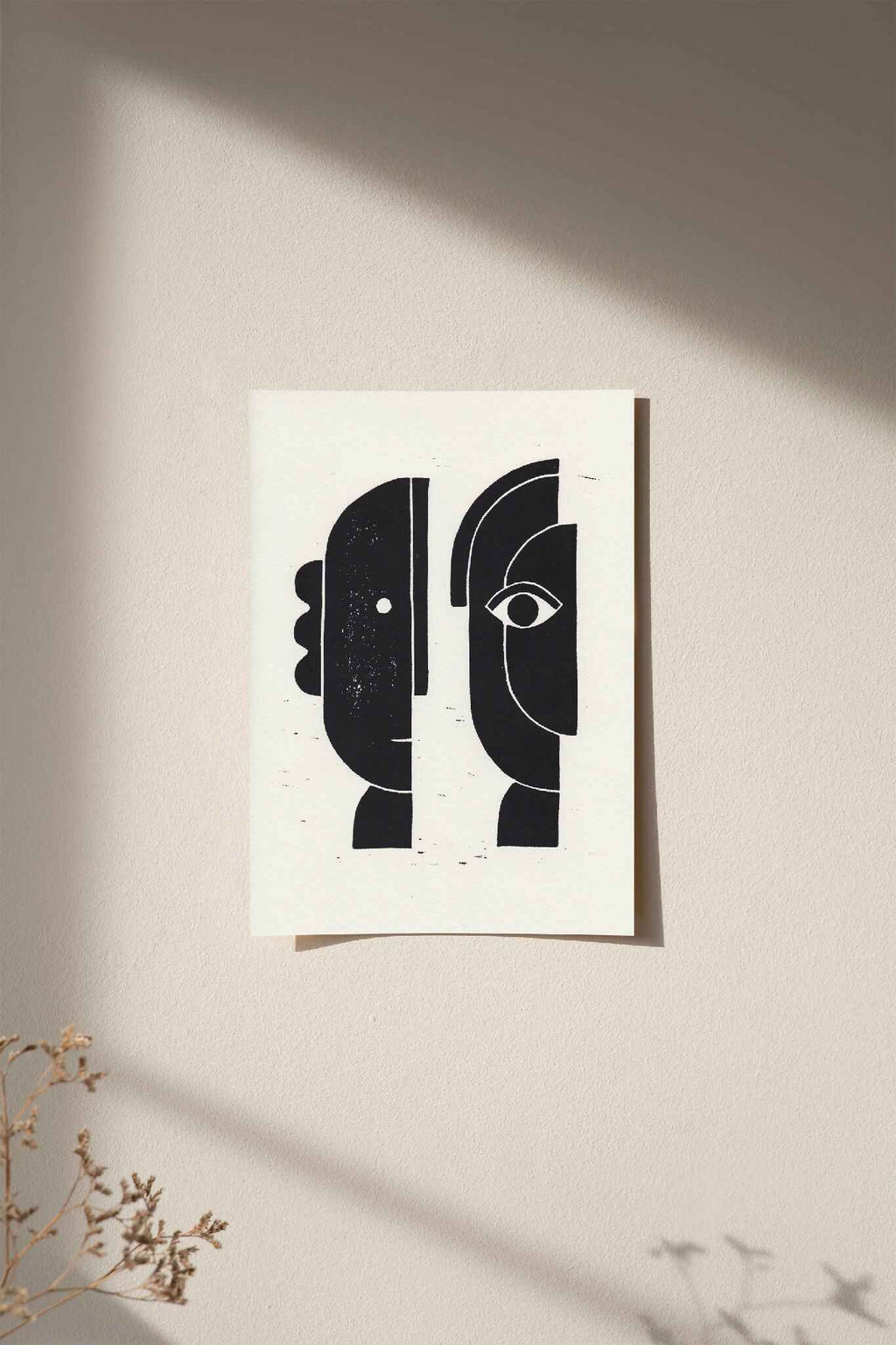 Linogravure encadrée, visages abstraits noirs sur fond clair.