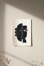 Linogravure encadrée, composition abstraite noir et blanc, cadre bois clair sur fond clair.