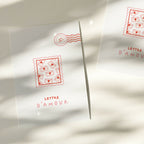 Carte de vœux blanche avec motif d’enveloppes rouges et tampon rond, vue partielle
