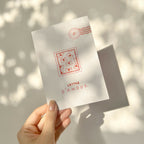 Carte de vœux blanche « Lettre d’amour » tenue par la main, motif d’enveloppes rouges