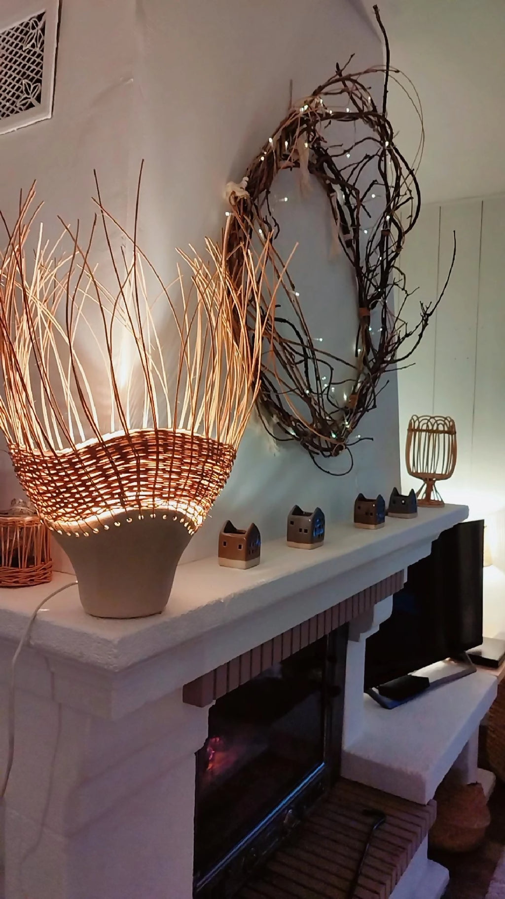 Luminaire en rotin brun tressé sur pot en grès, lumière chaude à l’intérieur.