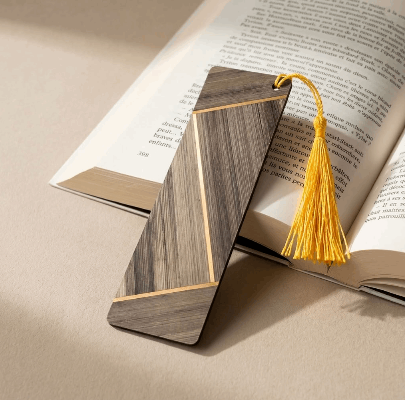 Marque-page en bois à marqueterie rayée marron, inséré dans un livre, gland jaune