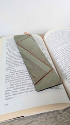 Marque-page en marqueterie de paille kaki, beige et touche cuivrée, sur livre ouvert