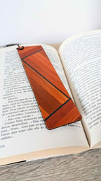 Marque-page en marqueterie de paille orange à lignes, posé sur un livre ouvert