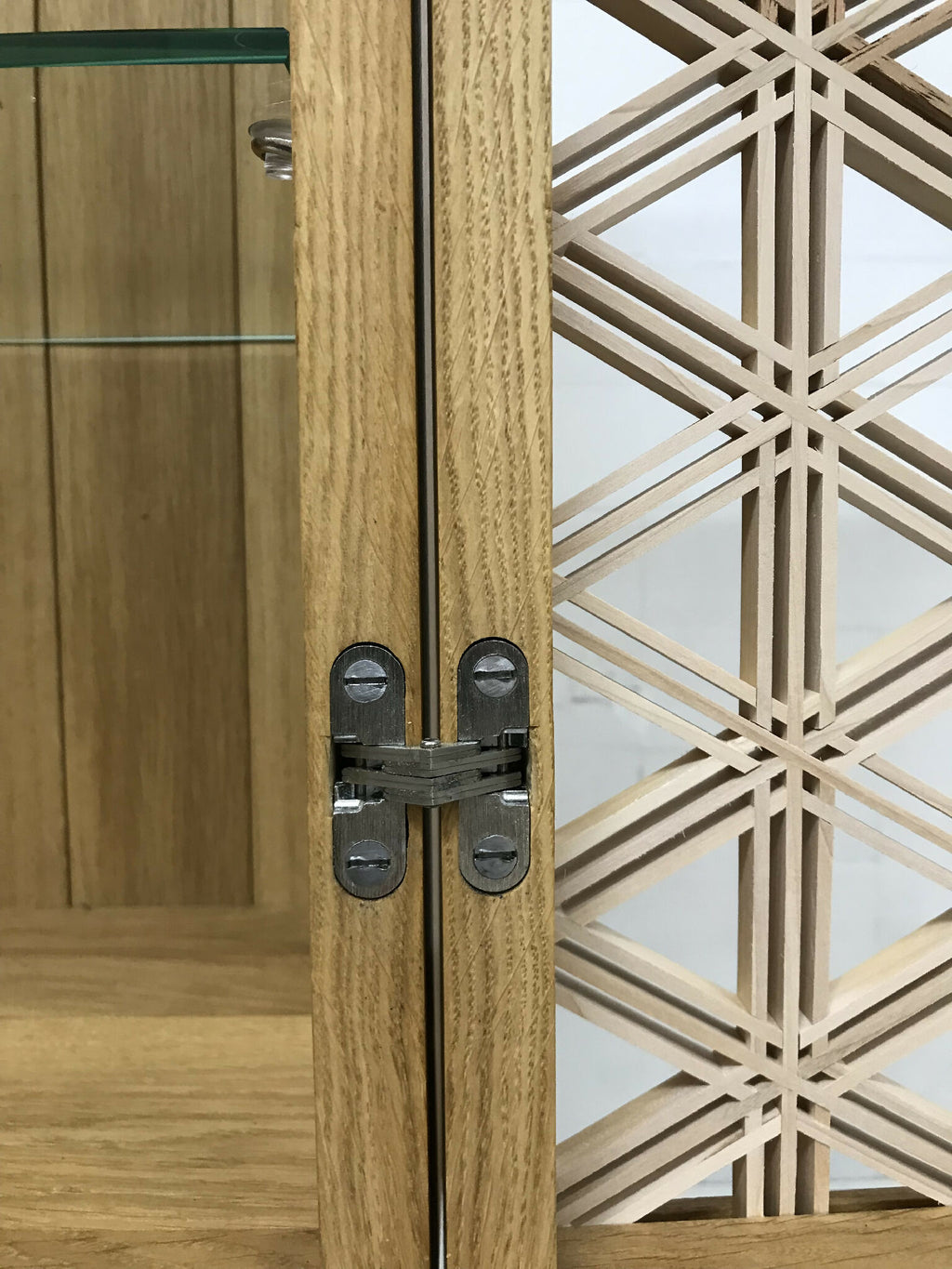 Poignées et charnières métalliques sur porte vitrine en chêne, panneau à croisillons.