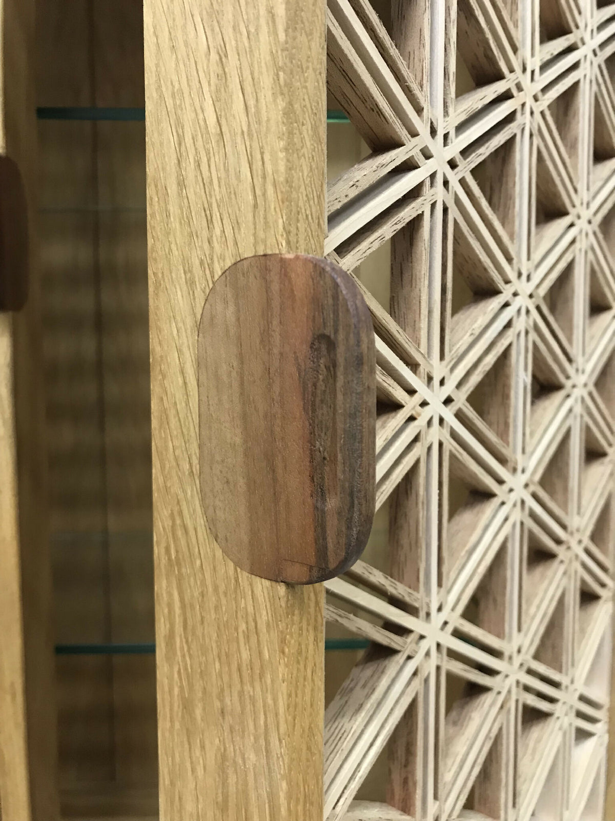 Détail du montant en chêne avec pastille ronde et panneau ajouré à croisillons.