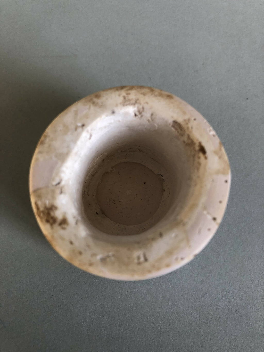 Petit pot en céramique rose pâle, intérieur visible avec traces et usure
