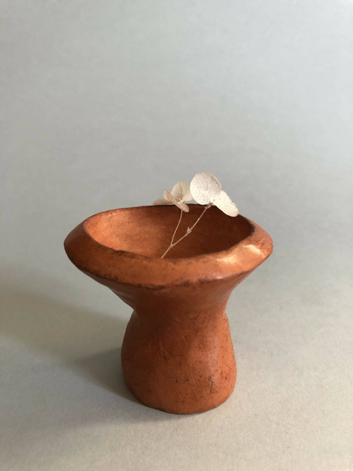 Mini pot en forme de sablier en céramique brune, avec fleur blanche sur le bord