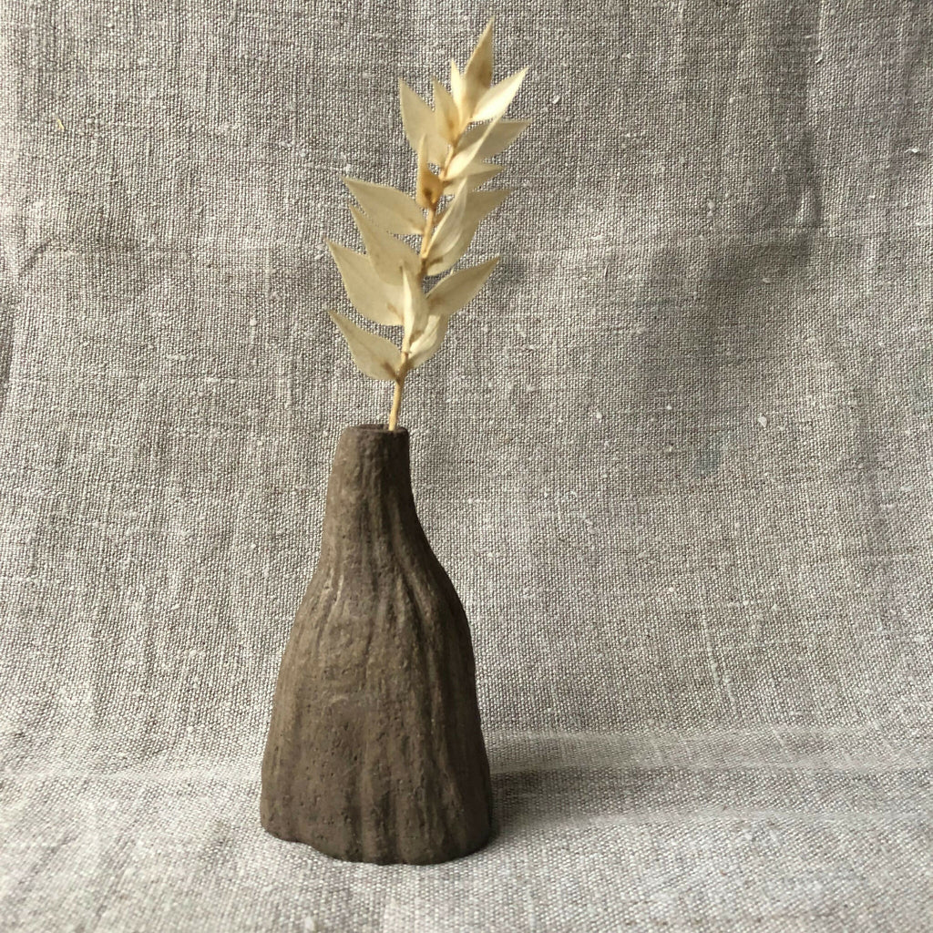Mini vase rainuré en terre sombre avec tiges d’herbes sèches beiges