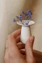 Vase en porcelaine blanc tenu dans la main, avec ouverture pour bouquet