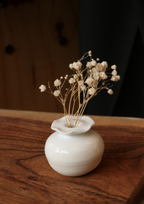 Mini-vase en porcelaine blanche sur table, fleurs séchées dans une petite urne