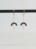 Boucles d’oreilles pendantes : demi-cercle noir, perle blanche, chaînette dorée.