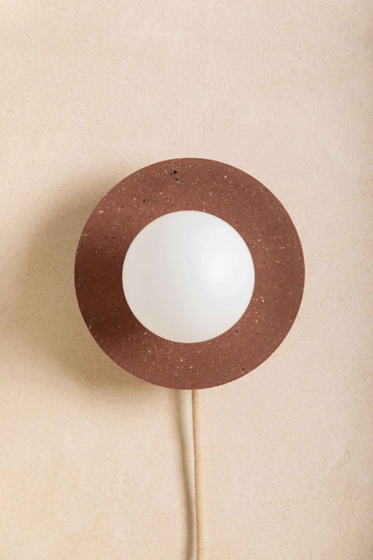 Applique murale ronde brun moucheté avec ouverture centrale et ampoule blanche, câble beige