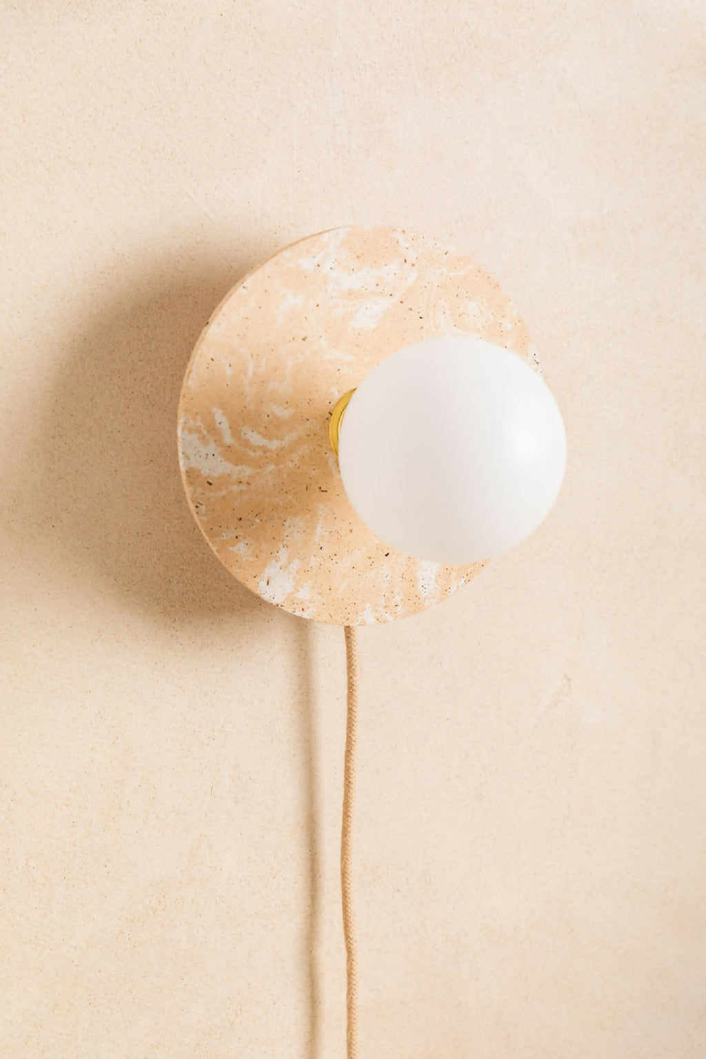 Applique murale ronde beige cuivré avec ouverture centrale et ampoule blanche, câble beige