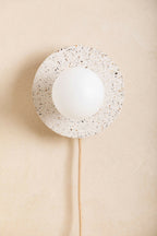 Applique murale ronde blanche mouchetée avec ouverture centrale et ampoule blanche, câble beige