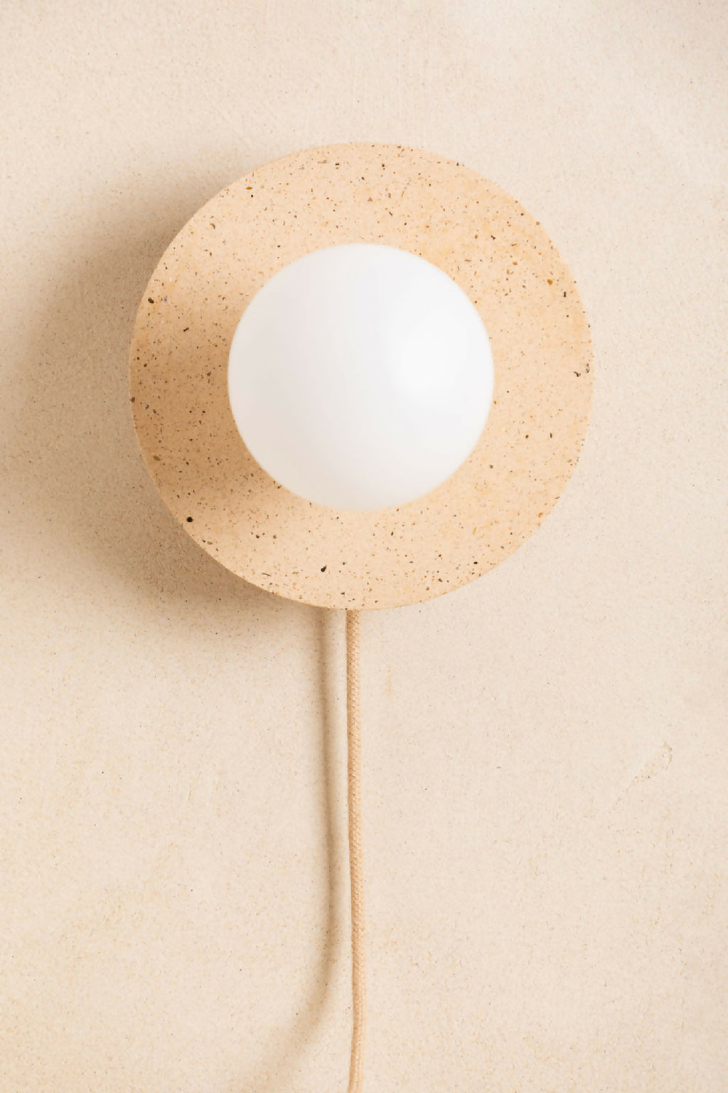 Applique murale ronde beige sablé avec ouverture centrale et ampoule blanche, câble beige