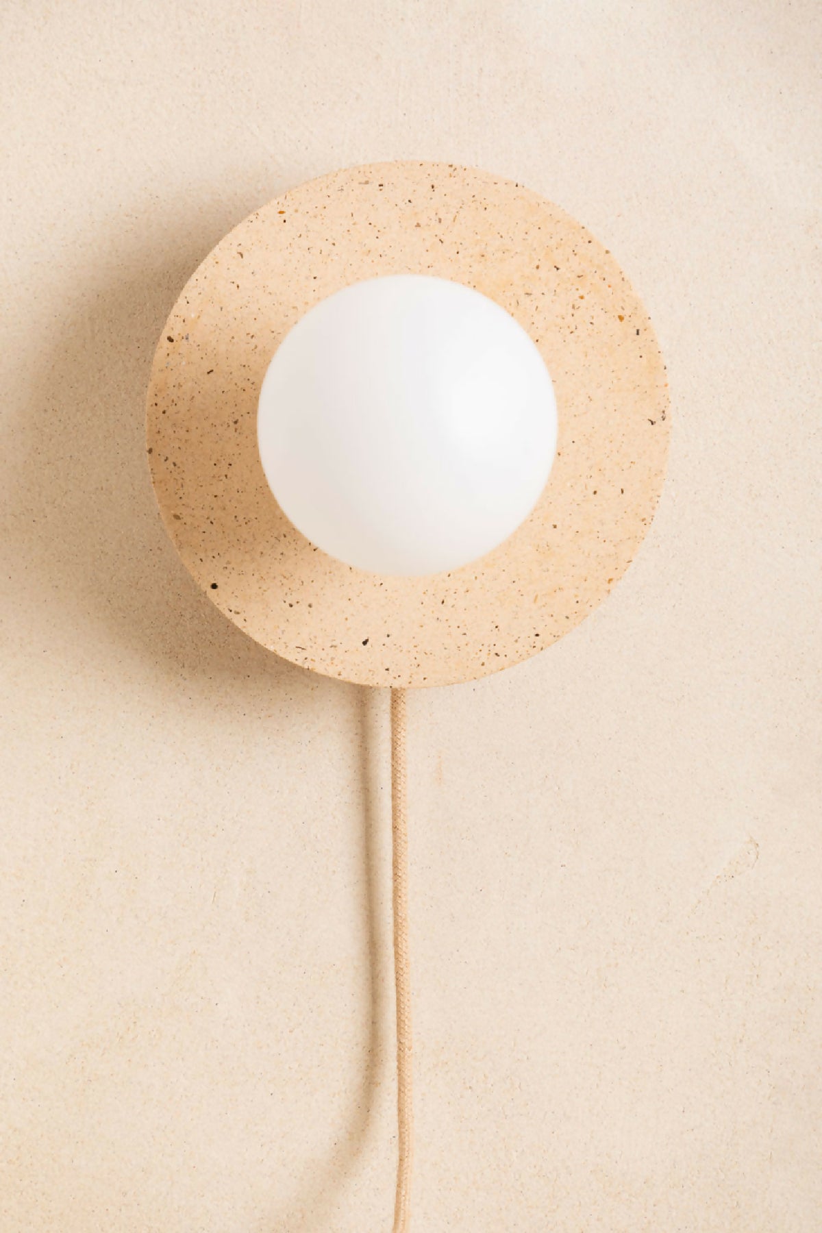 Applique murale ronde beige sablé avec ouverture centrale et ampoule blanche, câble beige