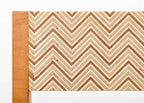 Détail du dossier de chaise : tissu beige à motif chevrons, bordure en bois.