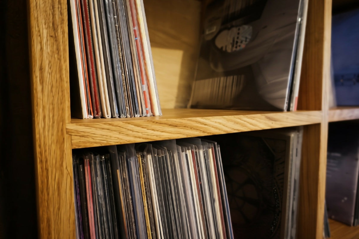 Étagère en bois avec rangées de vinyles visibles, bord horizontal au premier plan.