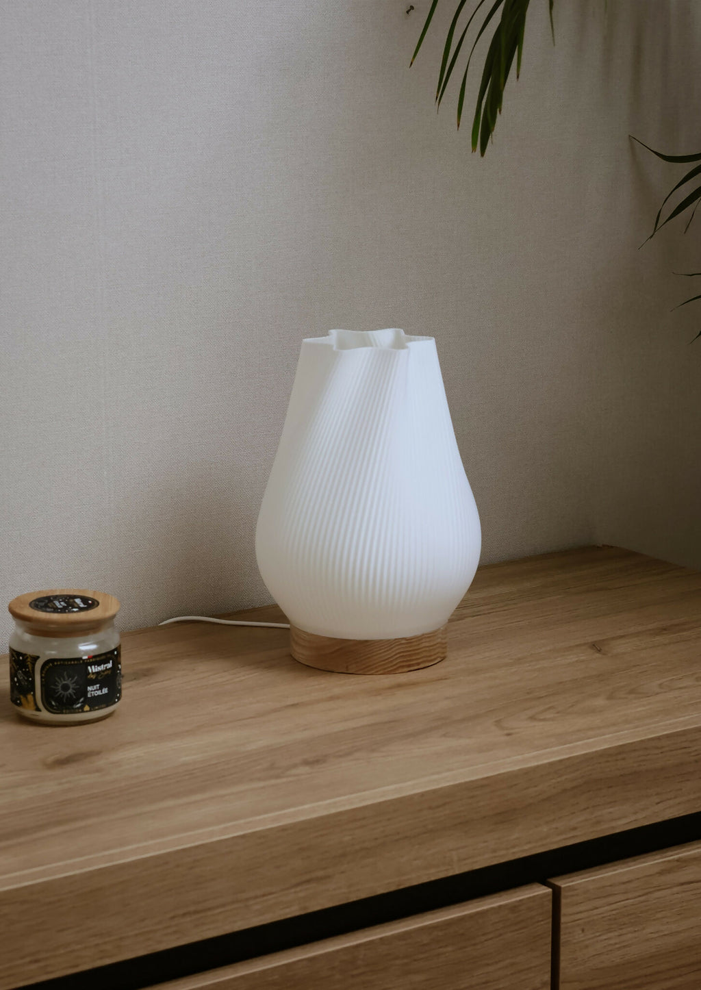 Lampe d’intérieur avec abat-jour blanc côtelé et base en bois sur une étagère.