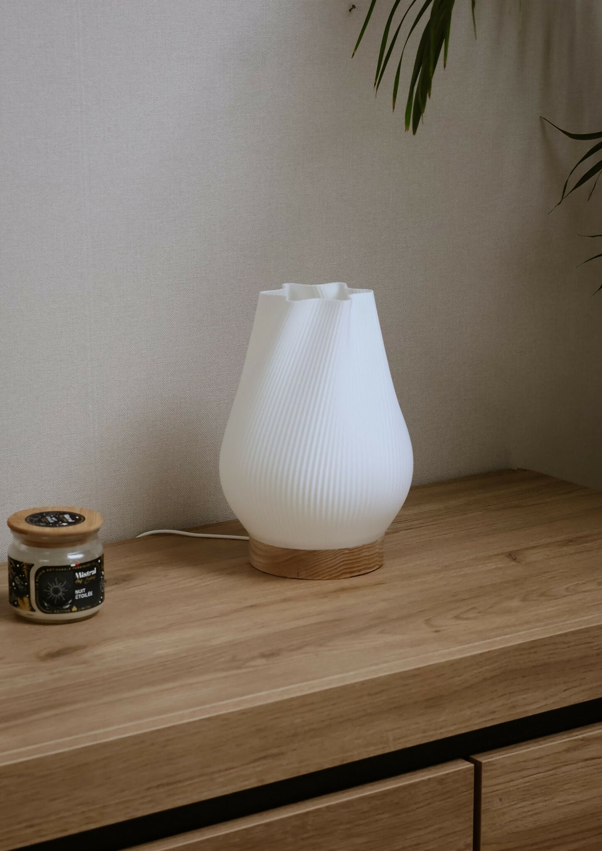 Lampe d’intérieur avec abat-jour blanc côtelé et base en bois sur une étagère.