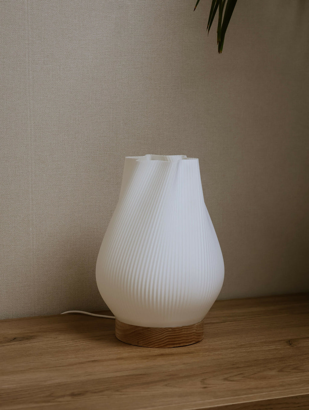 Lampe d’intérieur à abat-jour blanc côtelé avec base en bois, posée sur une étagère.